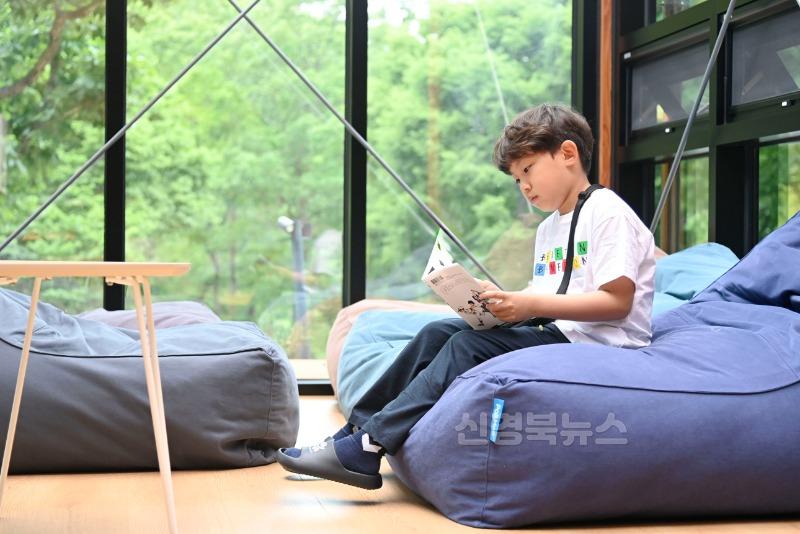2025년 05월 28일_비슬책방 정식 개관 사진 3(한 아이가 한장 한장 책장을 넘기며 비슬책방에서만 느낄 수 있는 특별한 독서 시간을 보내고 있다.).JPG