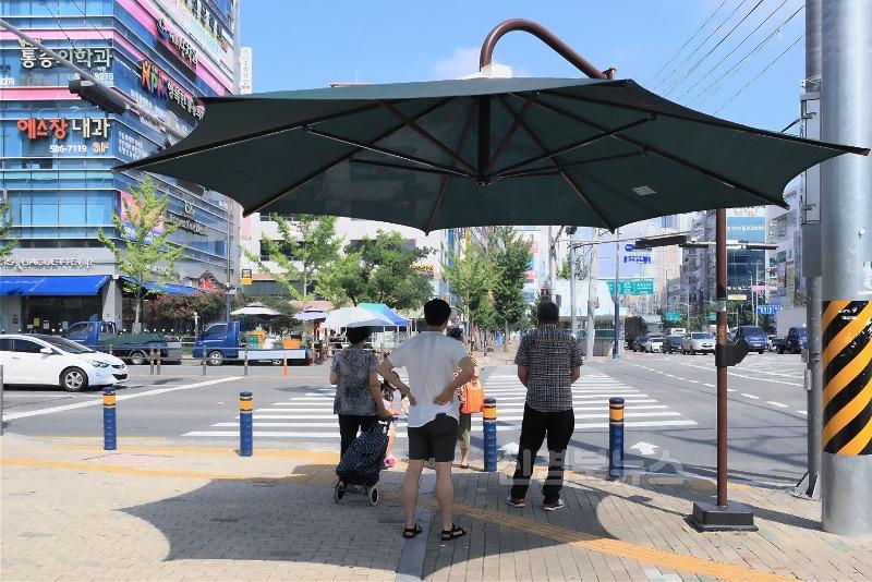 2025년 06월 09일_달성군, 행안부 공공빅데이터 분석 공모 3관왕 사진 2(무더운 폭염 속, 다사읍 대실역 인근에 설치된 그늘막 아래서 행인들이 횡단보도 신호를 기다리며 더위를 피하고 있다.).jpg